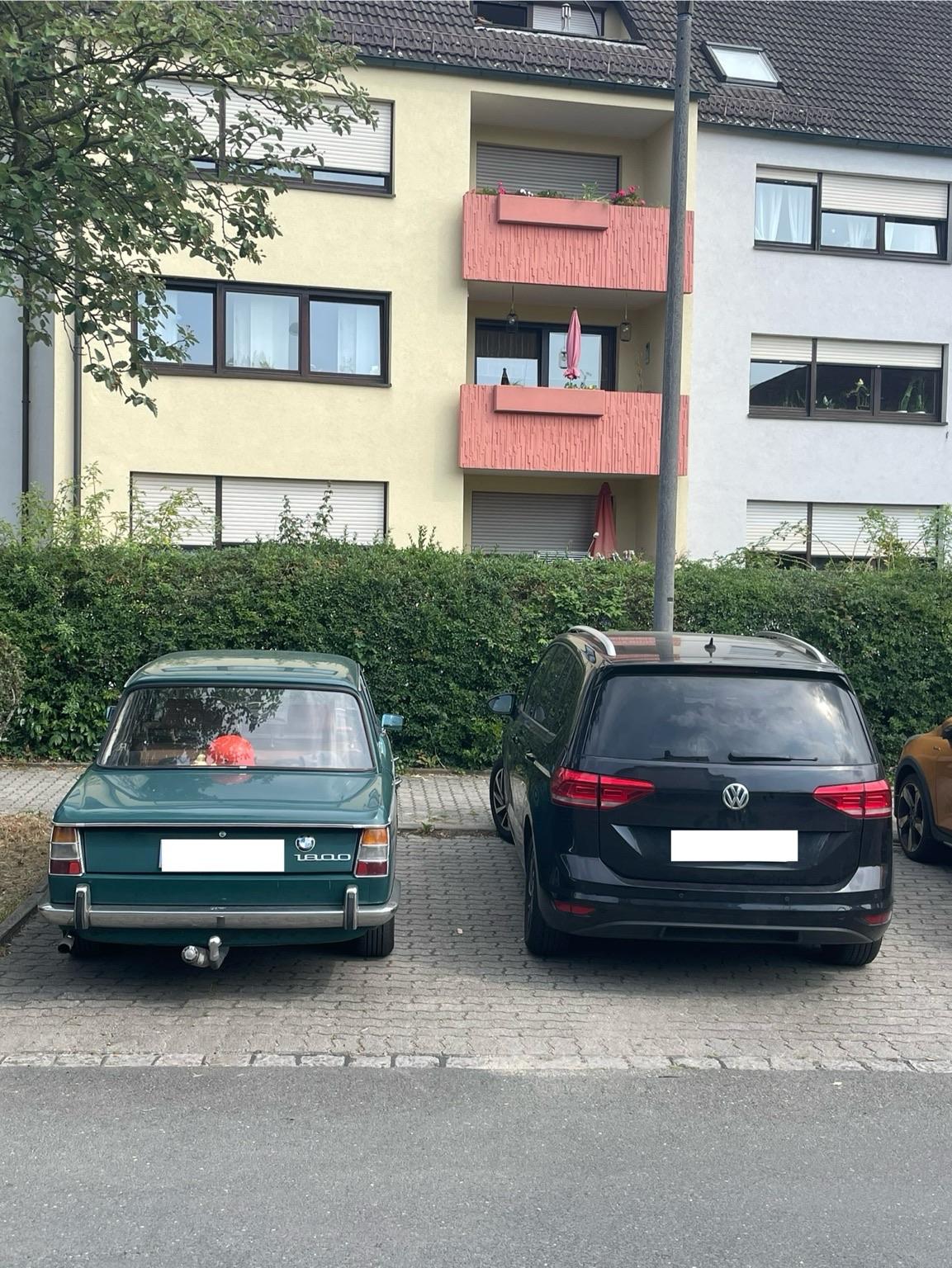 Altes BMW-Modell (BMW 1800) neben einem heutigen VW Touran